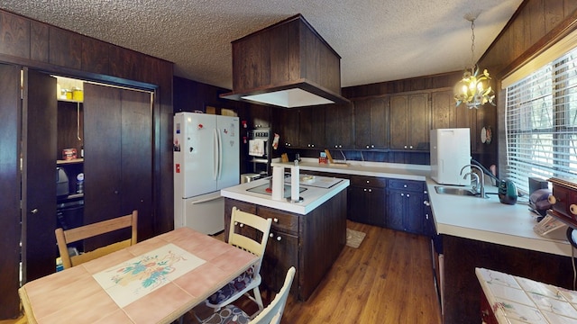 kitchen featuring a kitchen island, decorative light fixtures, sink, white refrigerator, and light hardwood / wood-style floors