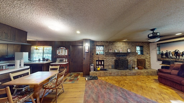 interior space with wood walls, a brick fireplace, dark brown cabinets, and a textured ceiling