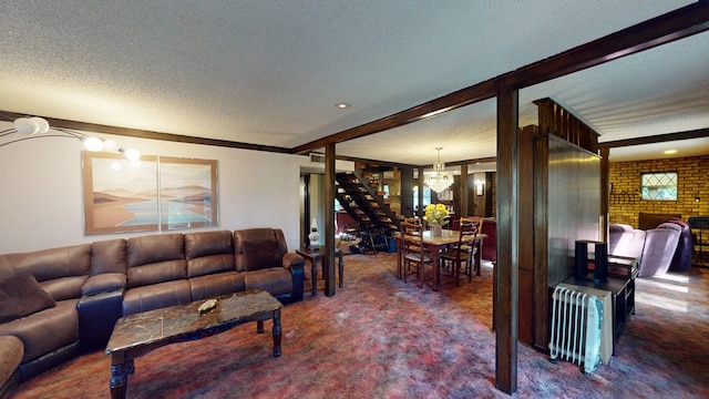 living room with a chandelier, a brick fireplace, a textured ceiling, radiator, and beam ceiling