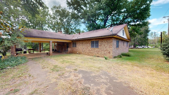 rear view of property with a yard and a carport