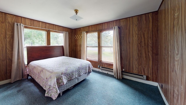 carpeted bedroom with wooden walls and baseboard heating