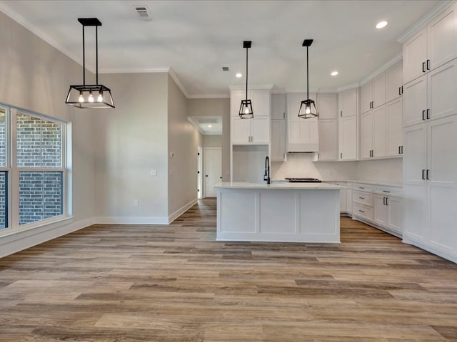 kitchen with light wood finished floors, visible vents, baseboards, light countertops, and ornamental molding