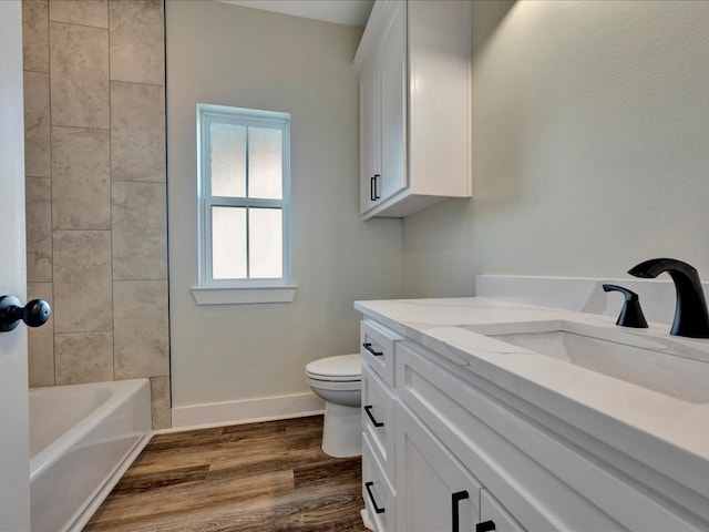 full bath featuring toilet, vanity, baseboards, and wood finished floors