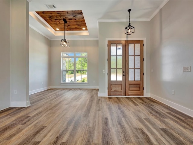 entryway with wood finished floors, baseboards, ornamental molding, french doors, and a raised ceiling