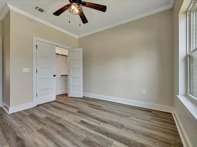 unfurnished bedroom with visible vents, baseboards, wood finished floors, and crown molding