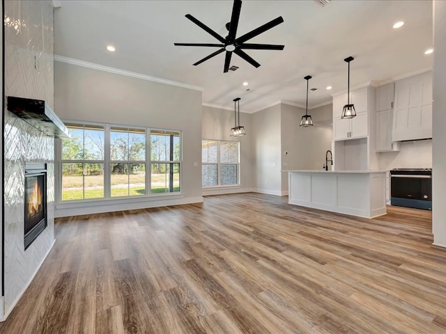 unfurnished living room featuring light wood-type flooring, ceiling fan, and ornamental molding