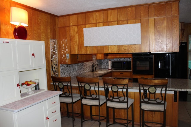 kitchen with white cabinets, light tile patterned floors, a kitchen bar, and oven