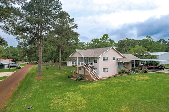 view of front of house with a front lawn, a sunroom, a carport, and stairs