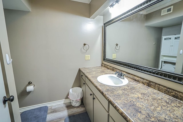 bathroom featuring baseboards, vanity, wood finished floors, and visible vents