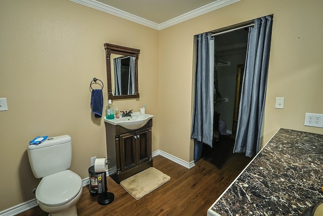 bathroom with wood finished floors, toilet, vanity, ornamental molding, and baseboards