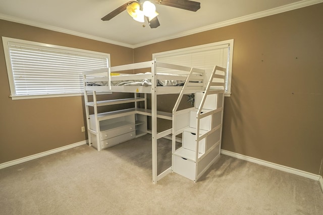 unfurnished bedroom with a ceiling fan, baseboards, crown molding, and carpet