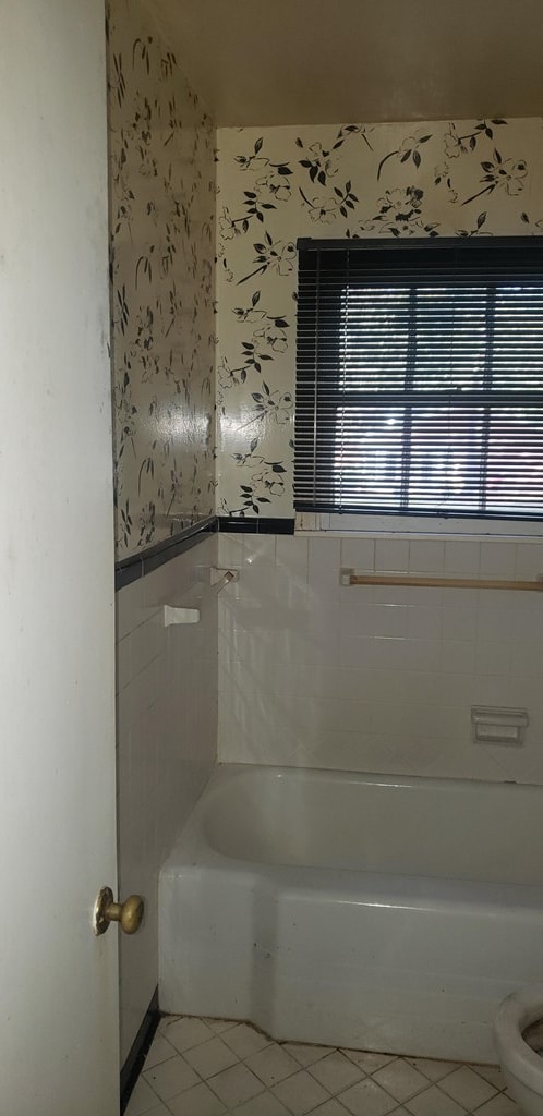 bathroom with tile patterned flooring, a washtub, and toilet