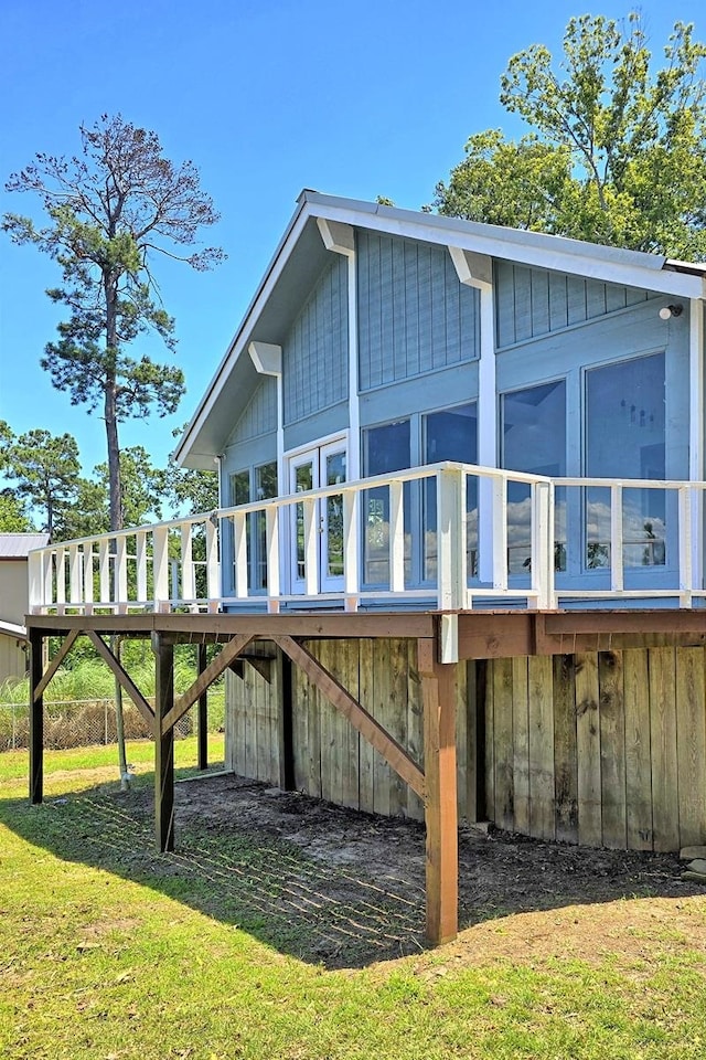 back of property featuring a wooden deck, a sunroom, and a yard