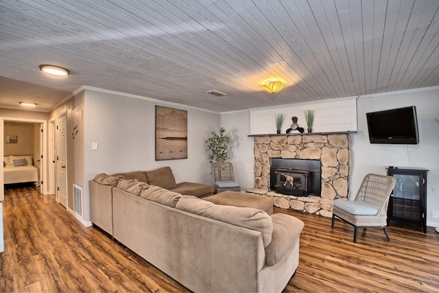 living room featuring visible vents, wood finished floors, baseboards, and ornamental molding