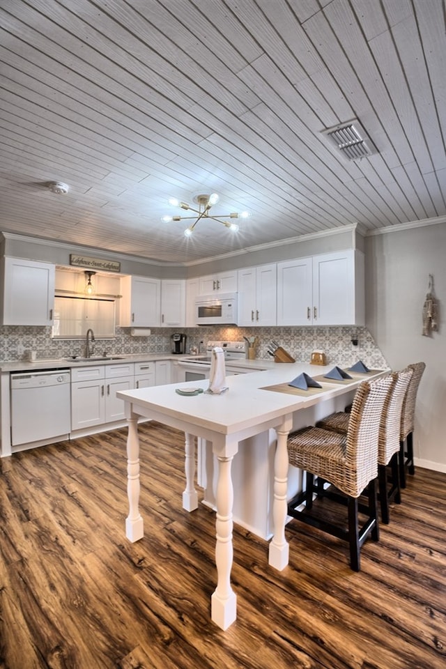 kitchen with ornamental molding, white appliances, a breakfast bar area, light countertops, and decorative backsplash