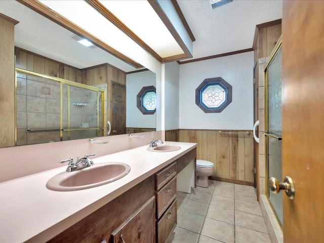 bathroom featuring tile patterned flooring, crown molding, a textured ceiling, toilet, and wooden walls