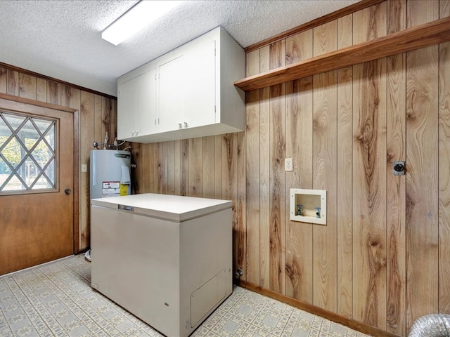 laundry room with cabinets, hookup for a washing machine, electric water heater, a textured ceiling, and wood walls