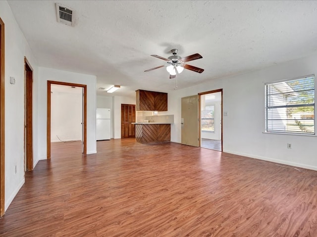 unfurnished living room featuring ceiling fan, hardwood / wood-style floors, a healthy amount of sunlight, and a textured ceiling