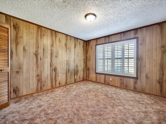 spare room featuring carpet flooring, a textured ceiling, and wooden walls