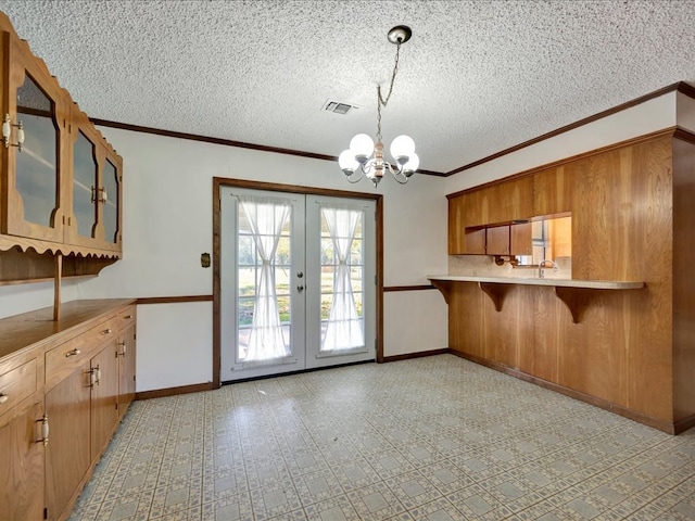 kitchen with french doors, a textured ceiling, decorative light fixtures, kitchen peninsula, and a chandelier