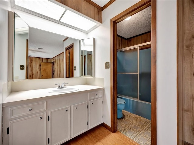 full bathroom with bath / shower combo with glass door, a textured ceiling, toilet, vanity, and hardwood / wood-style flooring