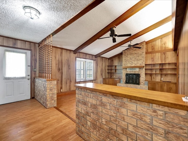 kitchen with vaulted ceiling with beams, a wealth of natural light, light hardwood / wood-style flooring, and wood walls