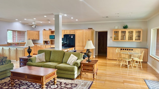 living room featuring decorative columns, sink, ornamental molding, ceiling fan, and light hardwood / wood-style floors