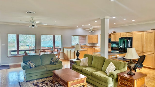 living room featuring ornate columns, ceiling fan, ornamental molding, and light wood-type flooring