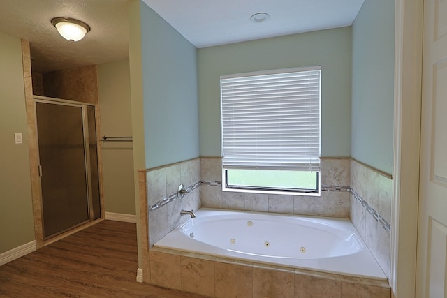 232 Cove Ln, Brookeland, TX 75931 - bathroom featuring a stall shower, a tub with jets, and wood finished floors