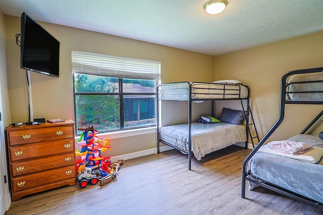 232 Cove Ln, Brookeland, TX 75931 - bedroom featuring wood finished floors, a textured ceiling, and baseboards