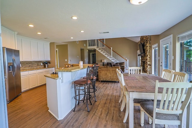 232 Cove Ln, Brookeland, TX 75931 - kitchen featuring stainless steel fridge with ice dispenser, light wood finished floors, recessed lighting, backsplash, and a breakfast bar