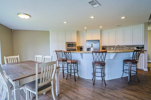 232 Cove Ln, Brookeland, TX 75931 - kitchen with stainless steel appliances, decorative backsplash, a breakfast bar, dark wood-style floors, and recessed lighting