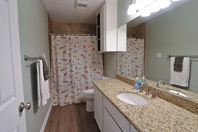 232 Cove Ln, Brookeland, TX 75931 - full bathroom with wood finished floors, vanity, toilet, curtained shower, and a textured ceiling