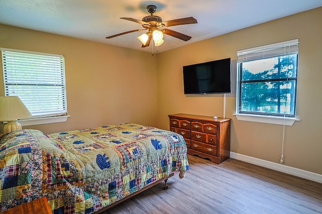 232 Cove Ln, Brookeland, TX 75931 - bedroom with wood finished floors, multiple windows, baseboards, and ceiling fan