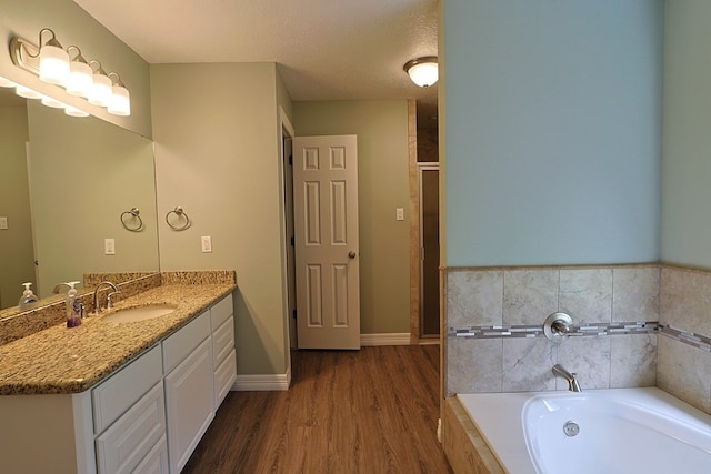 232 Cove Ln, Brookeland, TX 75931 - full bathroom featuring vanity, a garden tub, wood finished floors, and baseboards