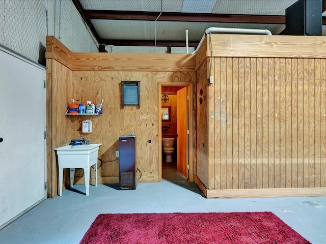 unfurnished bedroom with wood walls, sink, and concrete flooring