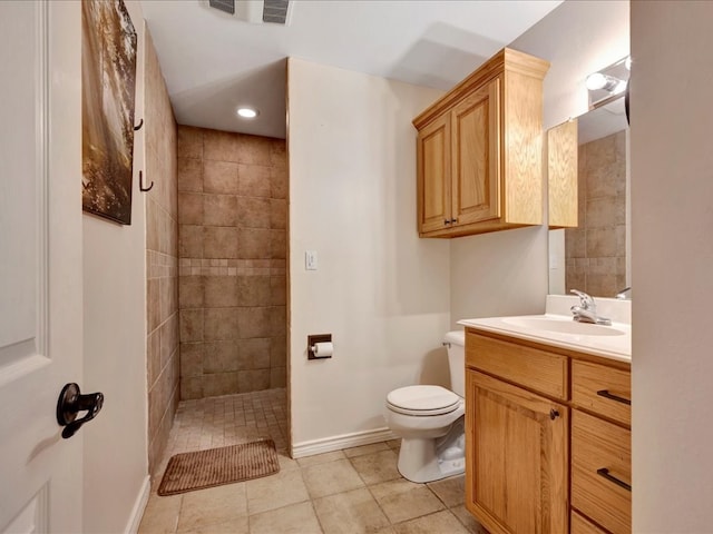 bathroom featuring a tile shower, tile patterned flooring, vanity, and toilet