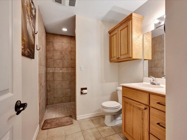 bathroom featuring a tile shower, tile patterned flooring, vanity, and toilet