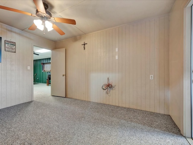 spare room featuring carpet flooring, ceiling fan, and wooden walls