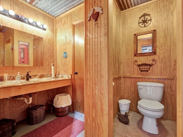 bathroom with tile patterned floors, toilet, wooden ceiling, and wooden walls