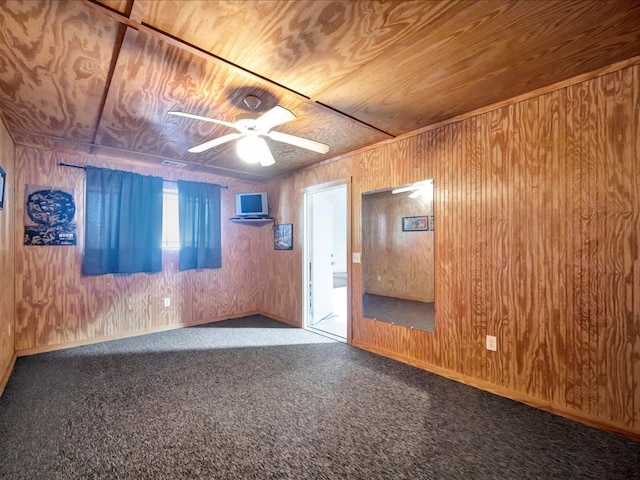 empty room featuring wooden walls, ceiling fan, and wooden ceiling