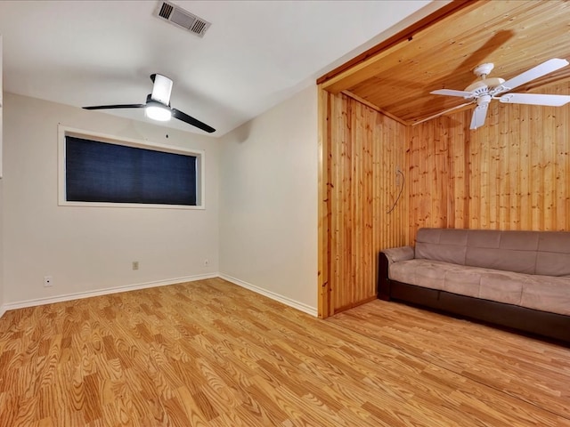 unfurnished living room featuring ceiling fan, wood walls, light wood-type flooring, and lofted ceiling