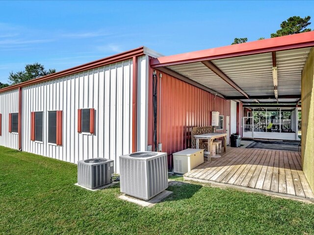 exterior space with central AC unit, a deck, and a yard