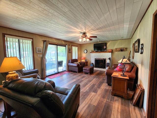 493 Hideaway Loop, Hemphill, TX 75948 - living area featuring a brick fireplace, ceiling fan, dark wood-type flooring, and wood walls