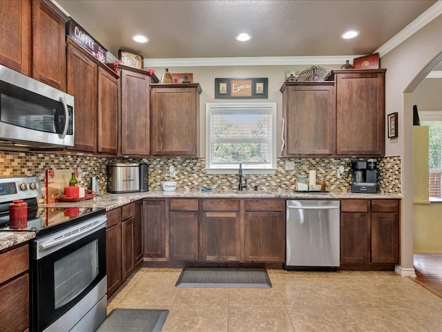 166 White Oak Ln, Lufkin, TX 75904 - kitchen with appliances with stainless steel finishes, ornamental molding, tasteful backsplash, light stone countertops, and light tile patterned floors