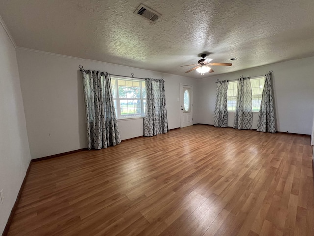 unfurnished room featuring ceiling fan, wood-type flooring, a textured ceiling, and ornamental molding