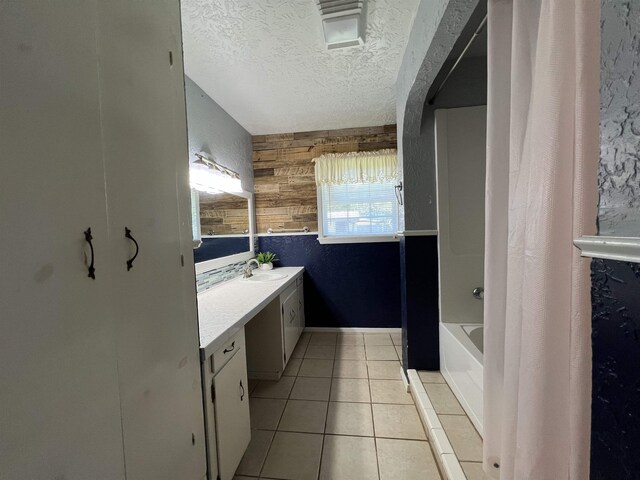 bathroom with shower / bath combination with curtain, tile patterned floors, a textured ceiling, vanity, and wood walls