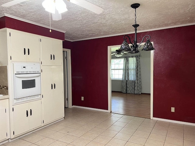 kitchen featuring white cabinetry, white oven, pendant lighting, light wood-type flooring, and ornamental molding