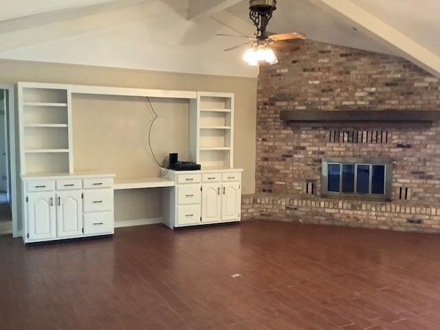 unfurnished office with vaulted ceiling with beams, ceiling fan, dark hardwood / wood-style flooring, and a brick fireplace