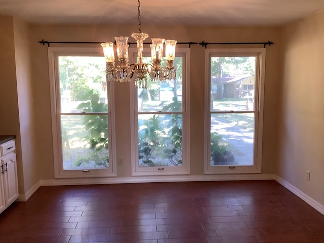 unfurnished dining area featuring a healthy amount of sunlight, dark hardwood / wood-style floors, and an inviting chandelier